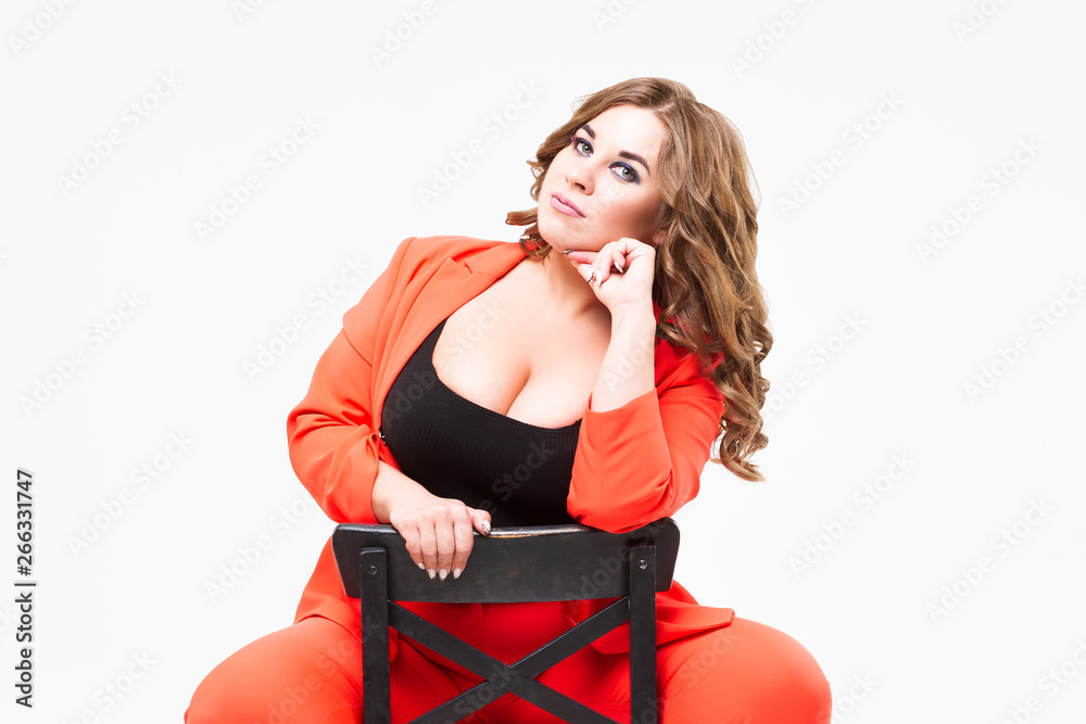 Plus size model with big breast and deep decollete, fat woman on white  background in orange pantsuit, body positive concept Stock Photo
