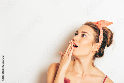 Studio portrait of impressed astonished young woman, closing open mouth with hand