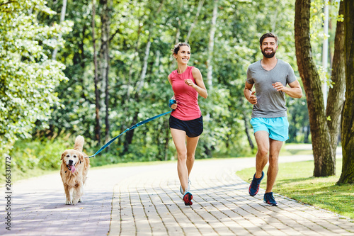 Happy couple running with dog in park