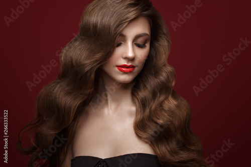 Beautiful brown-haired girl with a perfectly curls hair  and classic make-up. Beauty face and hair.