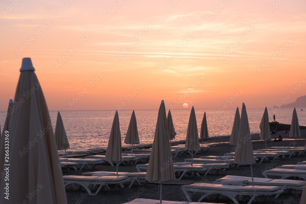 beach umbrella and the sun beds in the background orange soft sunset on the banks of the Mediterranean sea
