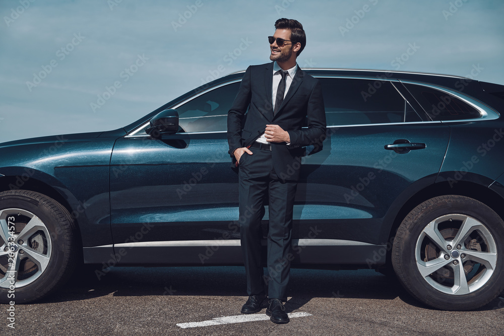 Great sense of style. Full length of handsome young businessman smiling while standing near his car outdoors