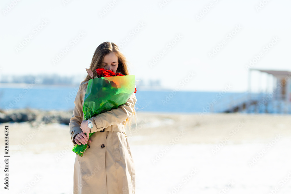 Young woman enjoys the smell of a bouquet of roses.