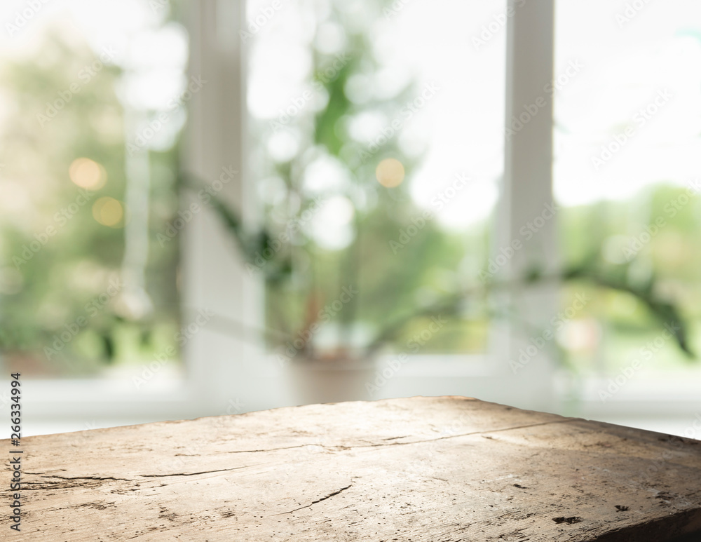 Wood table top on blur of window glass and abstract green from garden with city view in the morning background. For montage product display Wood table top on blur of window glass and abstract green from garden with city view in the morning background. For montage product display
