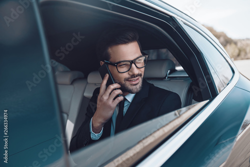 Pleasant talk. Thoughtful young businessman talking on the phone while sitting in the car © gstockstudio