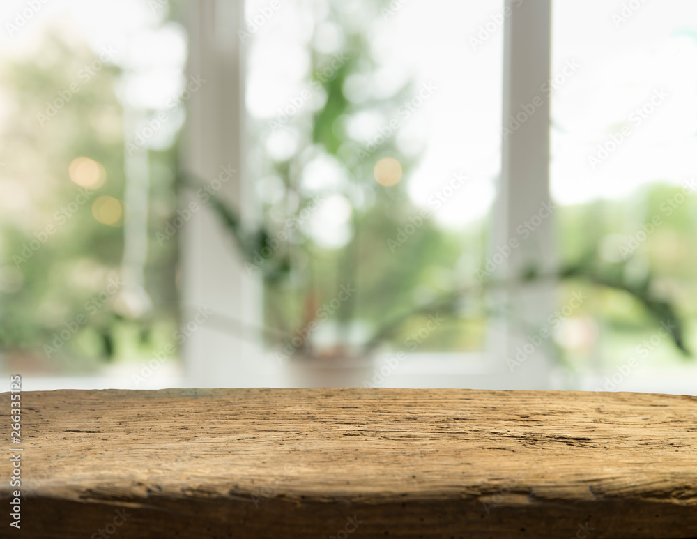 Wood table top on blur of window glass and abstract green from garden with city view in the morning background. For montage product display