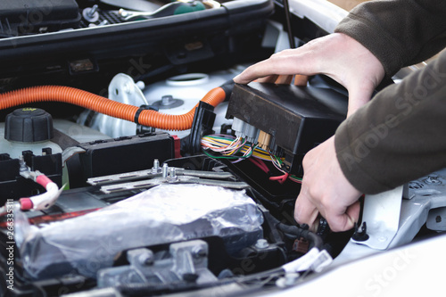 Mechanic checking the car fuse of electric car. © Андрей Репетий