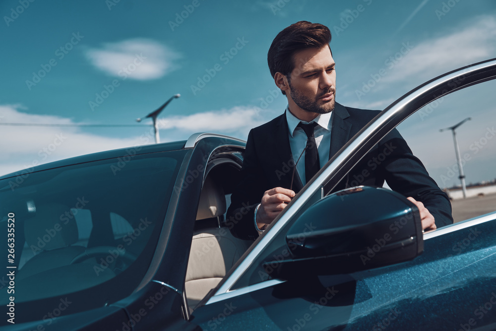 © gstockstudio - Business travel. Handsome young man in business wear entering his car while standing outdoors © gstockstudio - Business travel. Handsome young man in business wear entering his car while standing outdoors