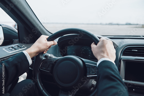 Drive carefully! Close up of man keeping hands on the steering wheel while driving a car © gstockstudio