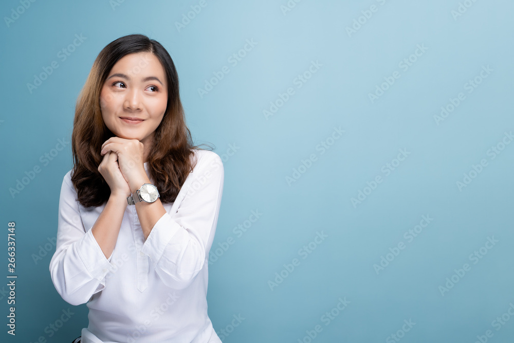 Happy woman thinking and standing isolated over blue background Happy woman thinking and standing isolated over blue background