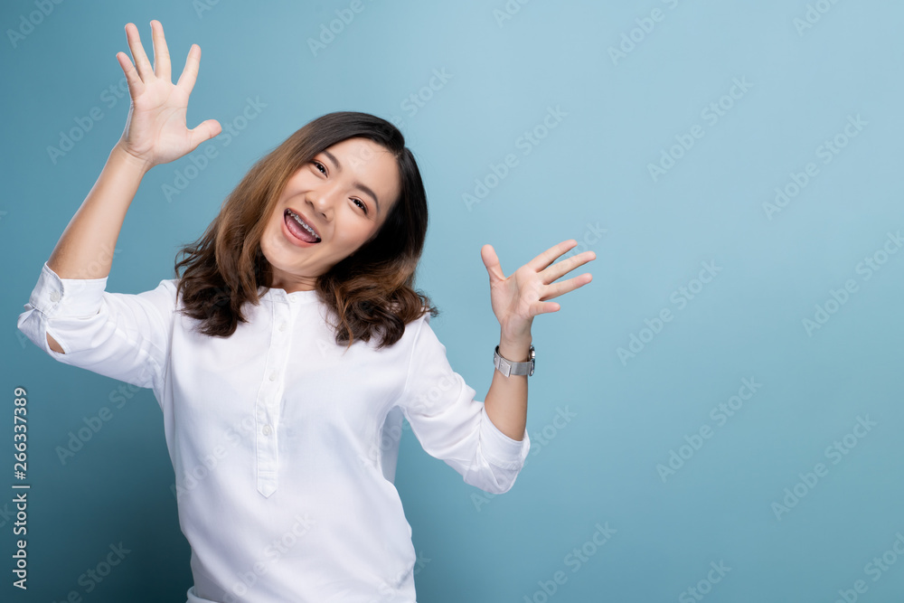 Happy woman make winning gesture isolated over blue background Happy woman make winning gesture isolated over blue background