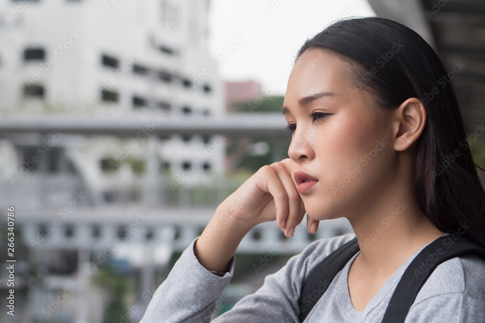 portrait of stressed, serious, pensive, thoughtful asian woman college student thinking in city campus environment