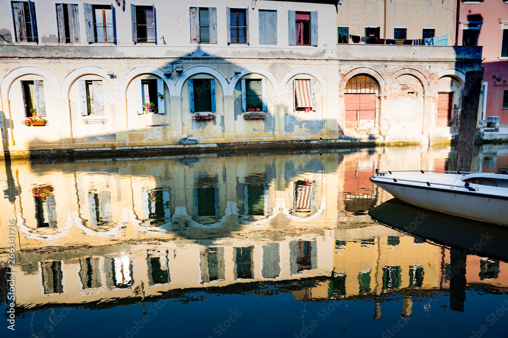 colorful houses and boat, reflection in canal of Chioggioa, Italy