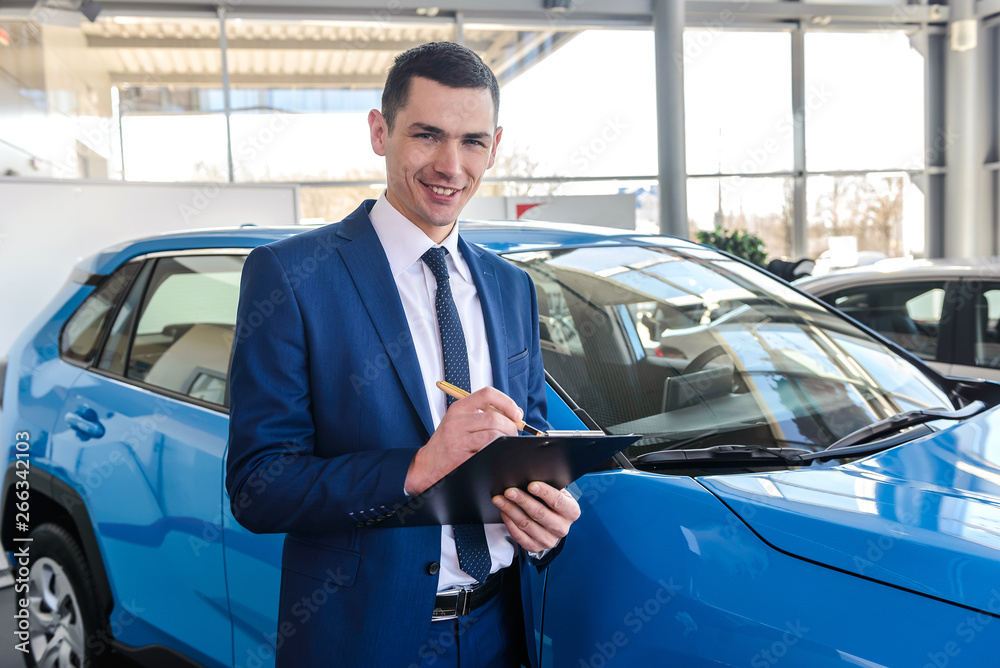Young car dealer holding clipboard in salon Young car dealer holding clipboard in salon