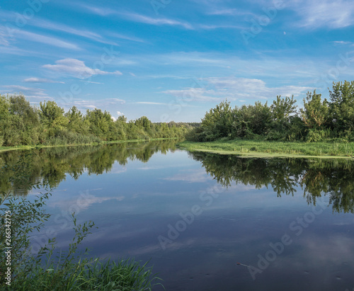 Beautiful summer landscape with pretty river and colorful trees. View of the sky with beautiful clouds. Stock photo
