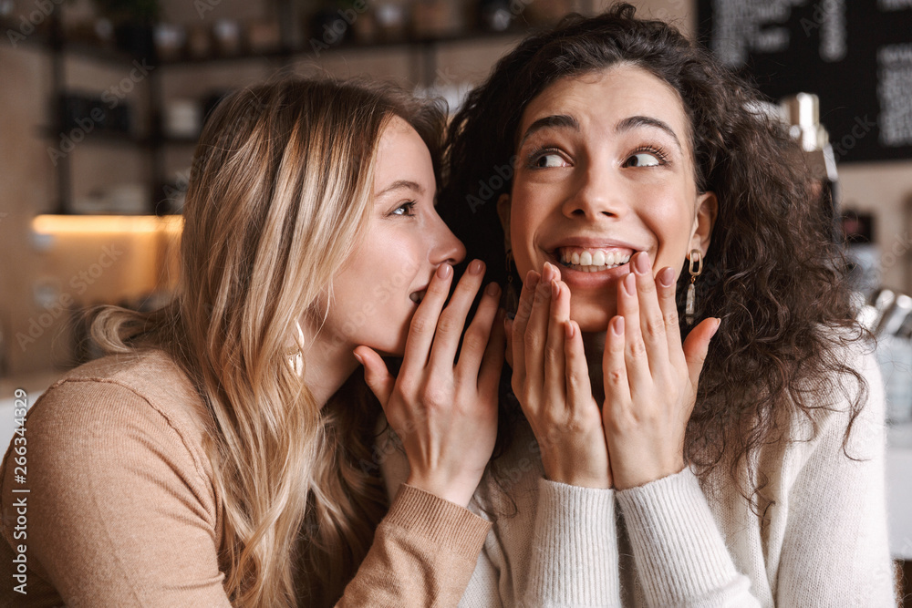 Girls friends sitting in cafe talking with each other gossiping. Girls friends sitting in cafe talking with each other gossiping.