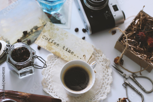 A Cup of coffee is on the table, next is a retro camera photo