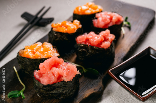 Salmon and tuna gunkan maki sushi roll set on wooden platter served with soy sauce and chopsticks. Japanese traditional culinary style, restaurant menu, food blog photo