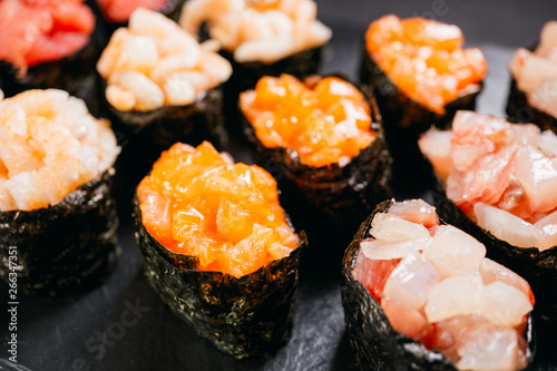Sushi set gunkan maki with salmon, tuna and prawn, flat lay on black stone slate. Delicious traditional Japanese meals, tasty seafood, restaurant menu concept, degustation, banquet, food background