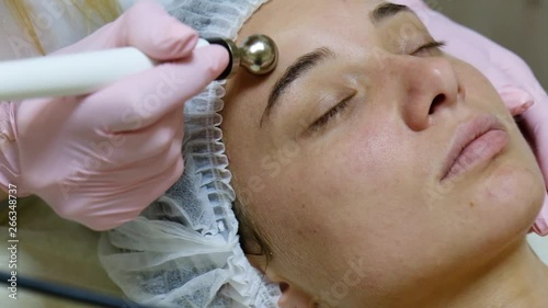 Young woman receiving electric galvanic anti-aging face spa massage at beauty salon. photo