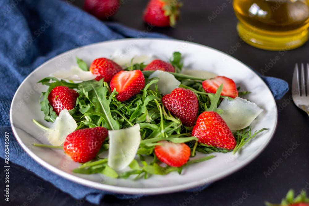 Salad of strawberries, arugula and cheese on a dark background. Dietary food. Salad of strawberries, arugula and cheese on a dark background. Dietary food.