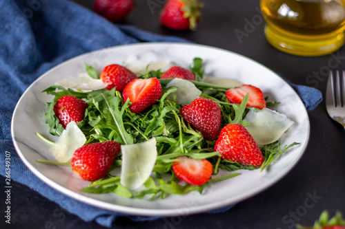 Salad of strawberries  arugula and cheese on a dark background. Dietary food.