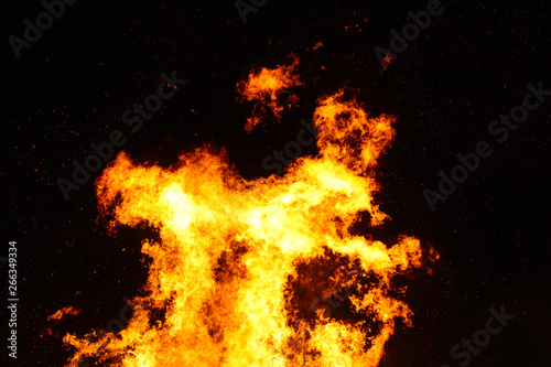 Large bonfire, burning and glowing with soft flames, sparkles flying agains the dark sky. Walpurgis night, traditional witch burning and spring welcoming ritual in the Czech Republic, April 30.