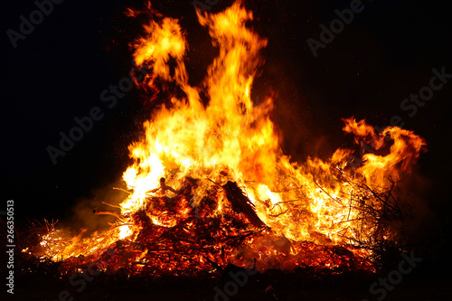Large bonfire, burning and glowing with soft flames, sparkles flying agains the dark sky. Glowing wood silhouettes. Walpurgis night, traditional witch burning and spring welcoming ritual. 30 April.