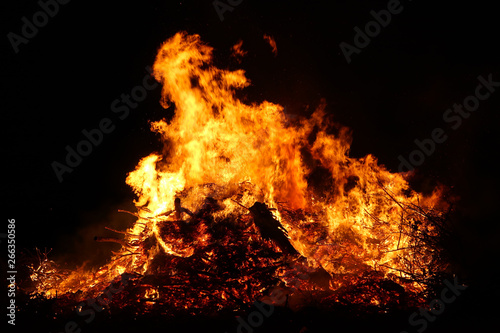 Large bonfire  burning and glowing with soft flames  sparkles flying agains the dark sky. Glowing wood silhouettes. Walpurgis night  traditional witch burning and spring welcoming ritual. 30 April.