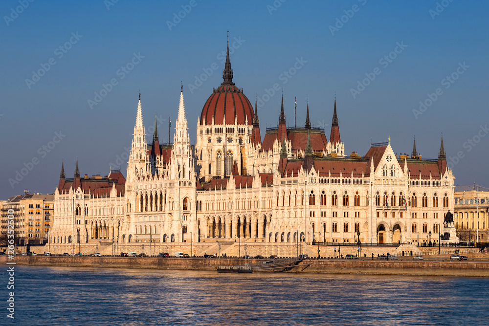 Hungary, Budapest: Famous Hungarian Parliament Building at sunny afternoon in the city center of the Hungarian capital with Donau Danube water, blue sky in background - travel architecture politics