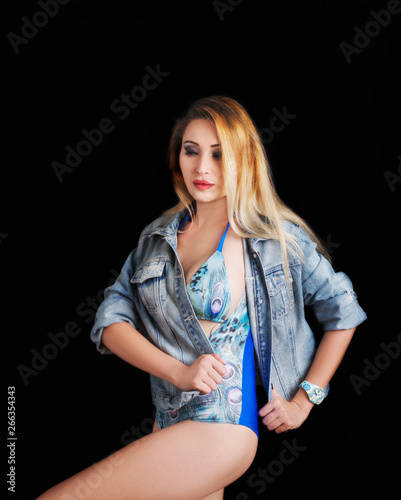 Young beautiful sexy girl posing in jeans jacket and fashionable swimsuit. Studio shot. © Victoria Key