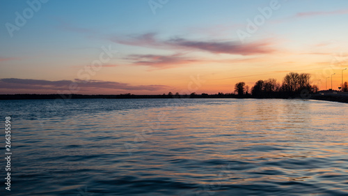 colorful sunset over the sea lake with dark red clouds
