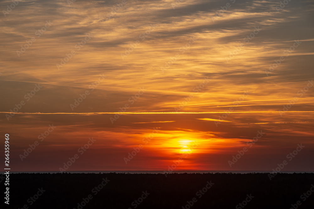 colorful sunset over the sea lake with dark red clouds