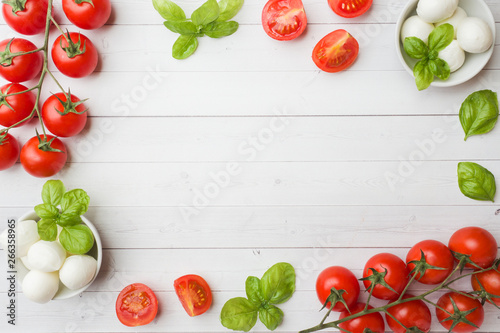 The ingredients for a Caprese salad. Basil, mozzarella balls and tomatoes on a white background with copy space.