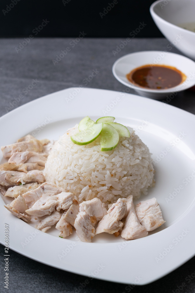 Hainanese chicken rice or rice cooked in chicken broth in the white dish.