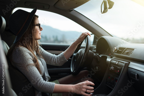 Fotografia Young hipster woman with eyeglasses and hat driving the car.