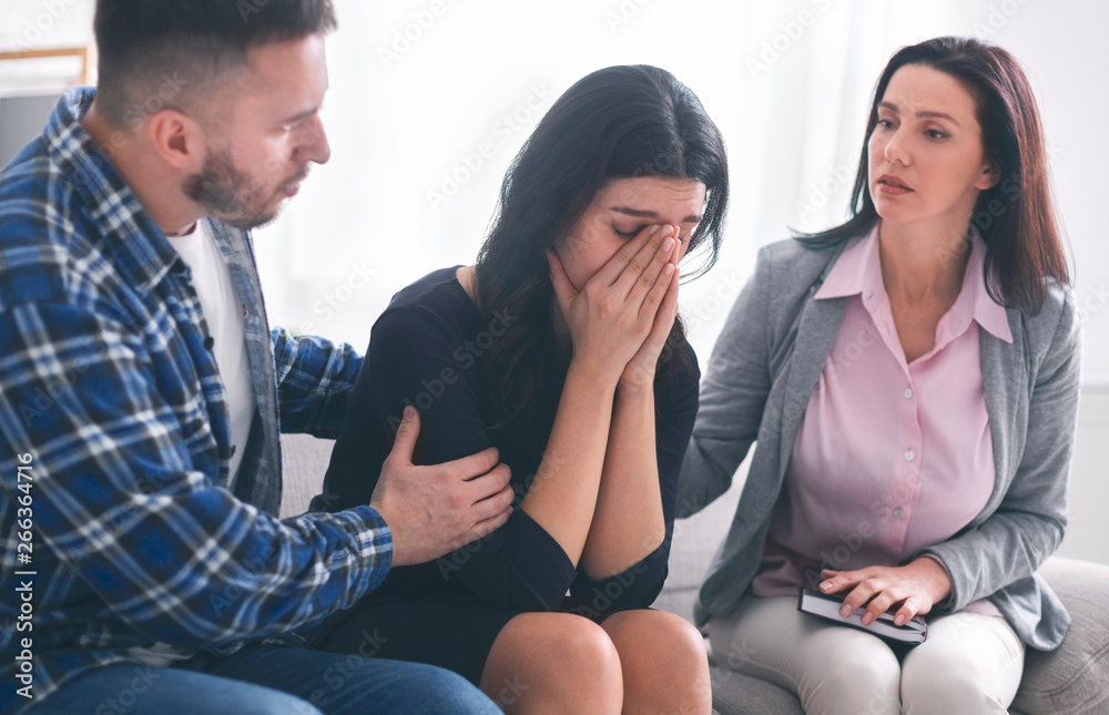 Psychologist comforting sad female patient in office