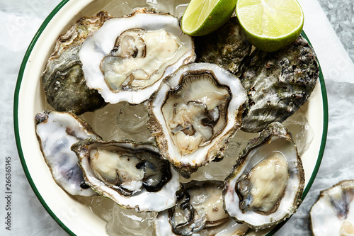 Raw Oysters served on ice in round enamel bowl photo