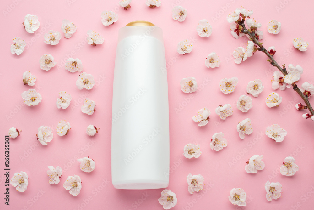Natural herbal shampoo concept. Cosmetic container with apricot blossoms on a light pink background. Blank label for branding mock-up, copy space.