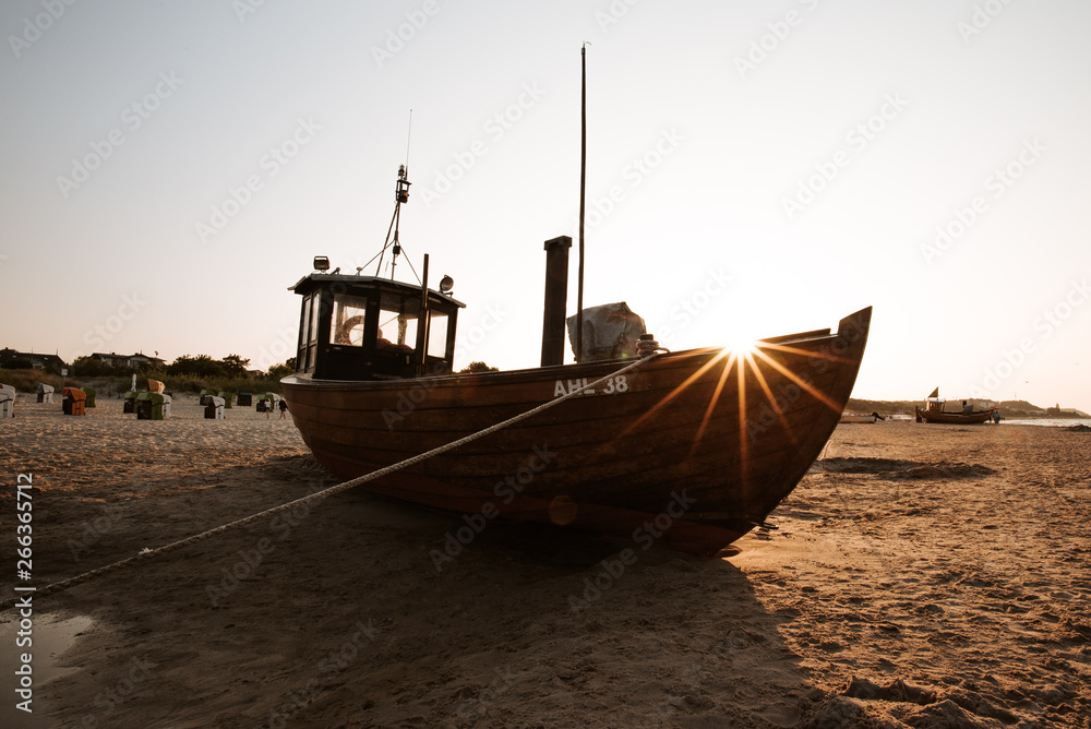 Fischerboot bei Sonnenuntergang am Strand im Sommer im Gegenlicht