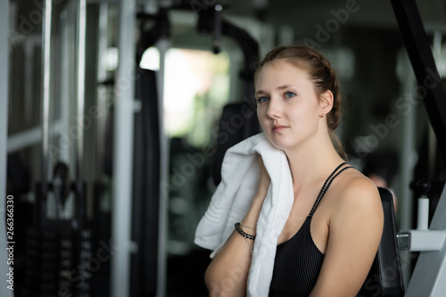 Young attractive woman caucasian sitting and using towel to wipe the sweat. Relaxation after hard workout in gym. Fitness concept, Healthy, Sport, Lifestyle