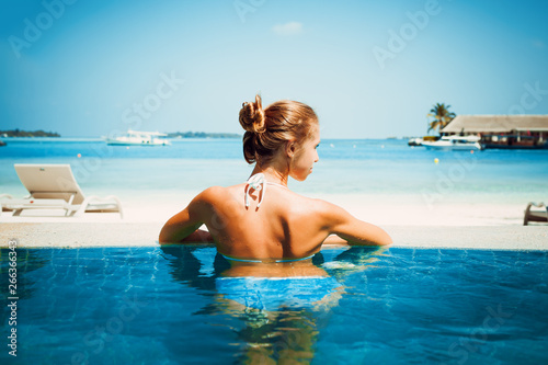 Travel vacation - Beautiful young pretty blonde girl back in bikini on her perfect sport sexy body relax in pool near paradise beach at tropical caribbean maldives beach at sunny day in hotel