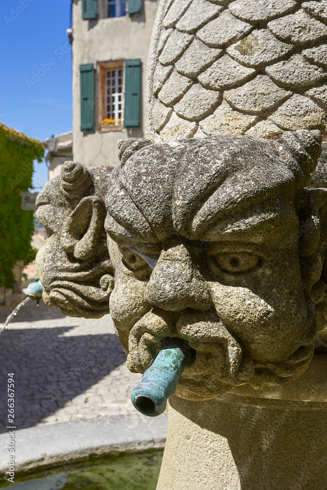 Stone demon head on water fountain in an old village Provence France Seguret Stone demon head on water fountain in an old village Provence France Seguret