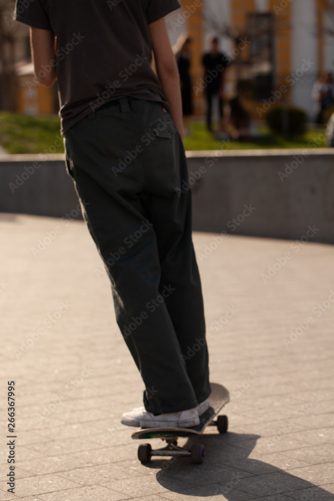 Young guys in stylish clothes ride a skateboard in the park. Young guys in stylish clothes ride a skateboard in the park.