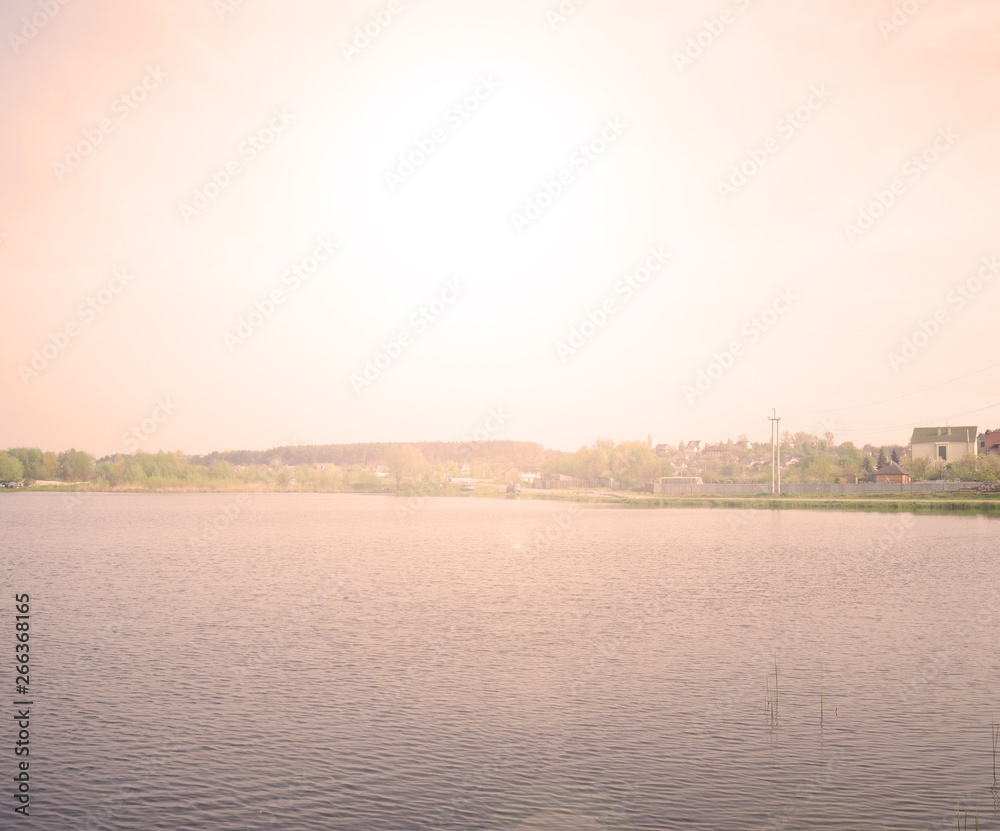 Beautiful sunset over a large lake in the village. Landscape evening summer.