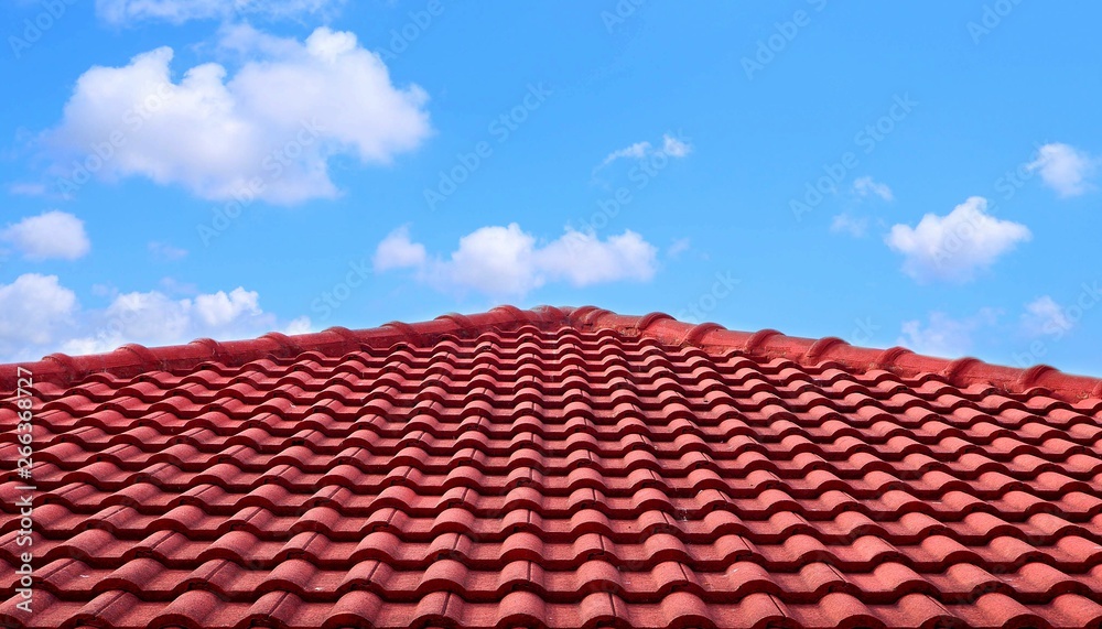 The old red tiles roof slope in pyramid shaped against white clouds and blue sky The old red tiles roof slope in pyramid shaped against white clouds and blue sky