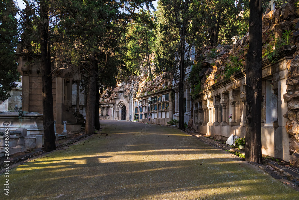 Perspective view of the curved footpath with graves and crypts on the Montjuic Cemetery in sunny day, Barcelona, Catalonia, Spain Perspective view of the curved footpath with graves and crypts on the Montjuic Cemetery in sunny day, Barcelona, Catalonia, Spain