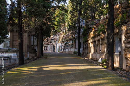 Perspective view of the curved footpath with graves and crypts on the Montjuic Cemetery in sunny day, Barcelona, Catalonia, Spain