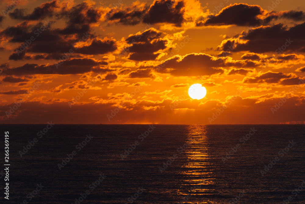 orange sky as glowing sun rises over the ocean