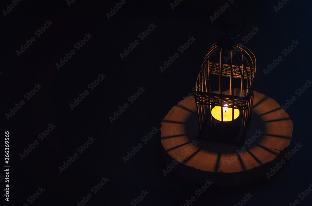 Beautiful Lantern that have moon symbol on top that have light from candle shining on wooden tray with dark background for the Muslim feast of the holy month of Ramadan Kareem.